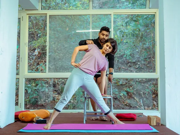 Yoga instructor guiding a member through a side stretch